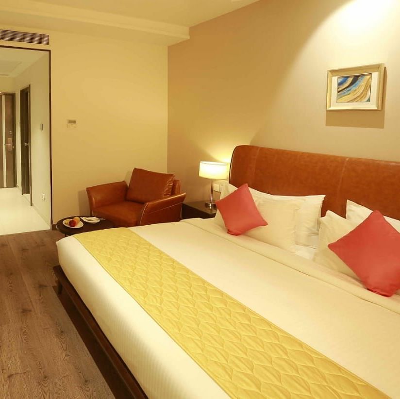 Executive Room at Mayberry Tiruppur with a view of the bed, sofa, and wall-mounted TV, with the room door visible in the background